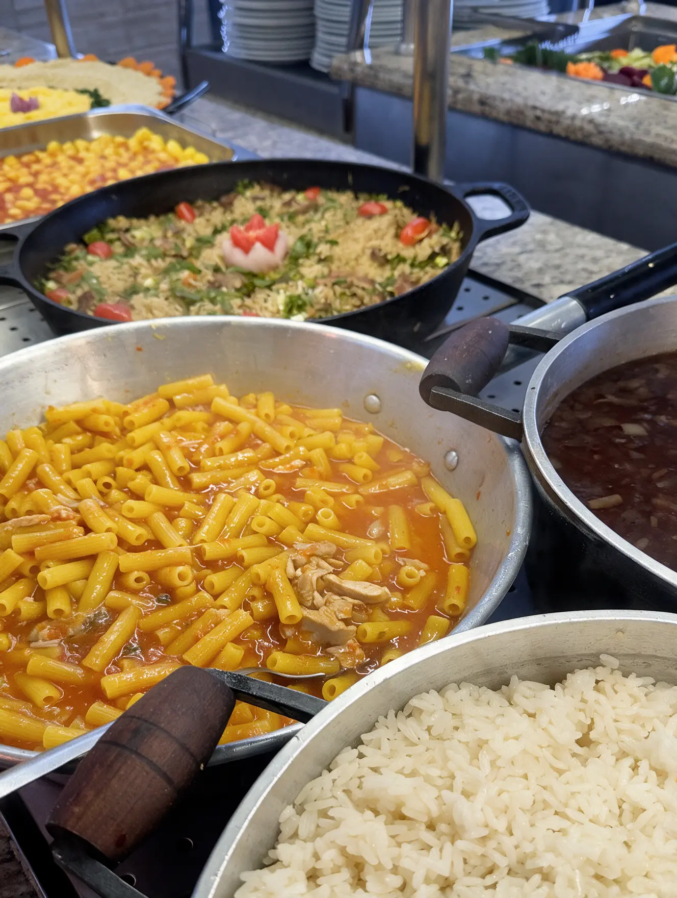 Buffet quente com massas, arroz e feijão